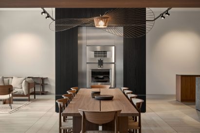 Ten-seater dining table with statement light fixture above and oven at other end