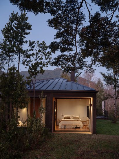 View into bedroom with large glass window and trees outside