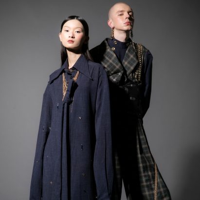 Photograph showing two models in dark clothing on dark backdrop
