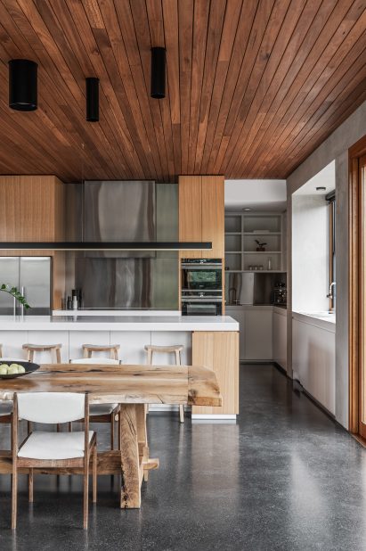 Open-plan kitchen and dining area with timber-lined ceiling and custom oak table