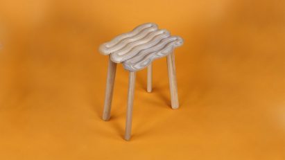 Curved wood stool on an orange background by design courses