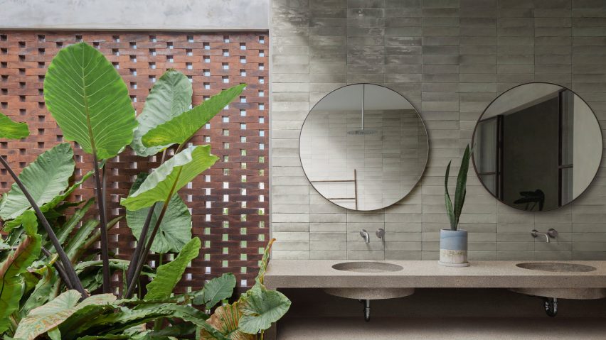 Photograph of bathroom with beige tiles laid horizontally behind sinks and mirrors