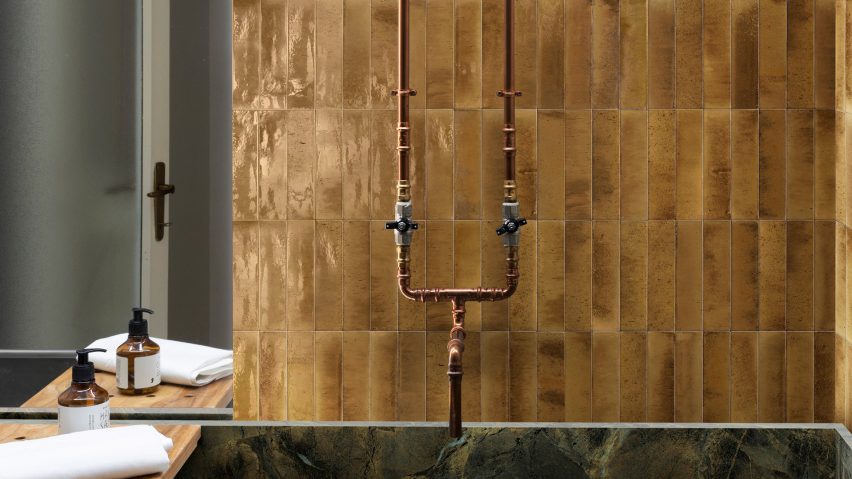 Photograph of bathroom with golden tiles laid vertically behind bath