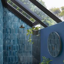Photograph of bathroom with dark blue tiles laid vertically inside shower enclosure