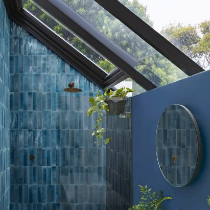 Photograph of bathroom with dark blue tiles laid vertically inside shower enclosure