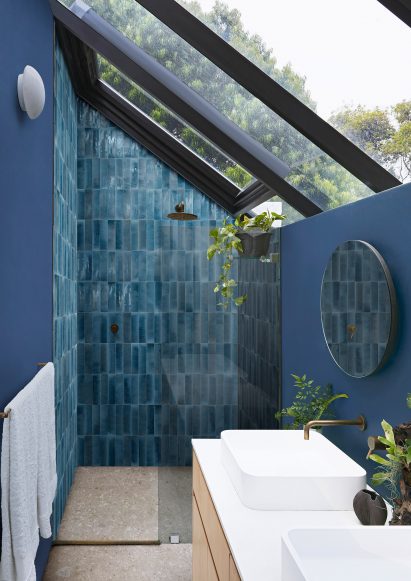 Photograph of bathroom with dark blue tiles laid vertically inside shower enclosure