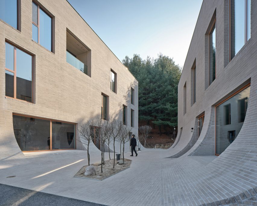 Concrete brick courtyard at Cafe Teri by Nameless Architecture with two facing buildings