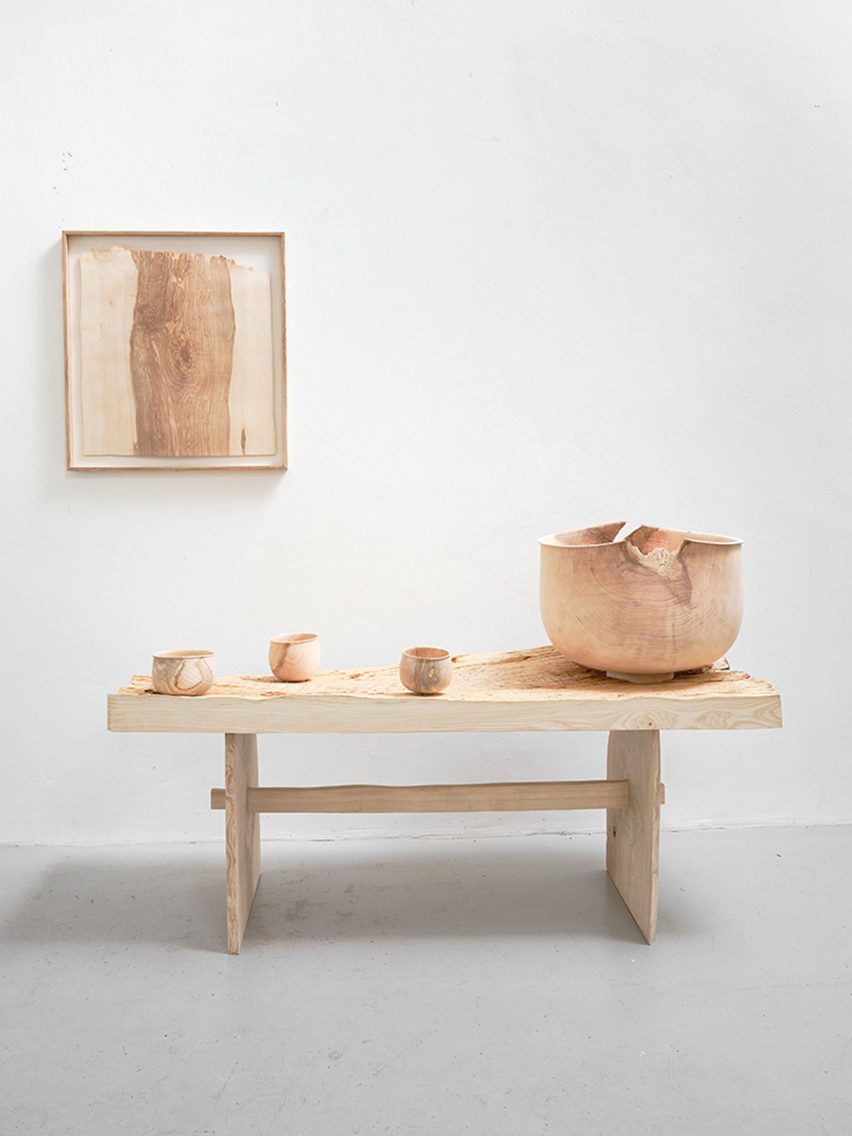 Photograph showing wall hanging, bench with bowls on top all made from wood on white backdrop