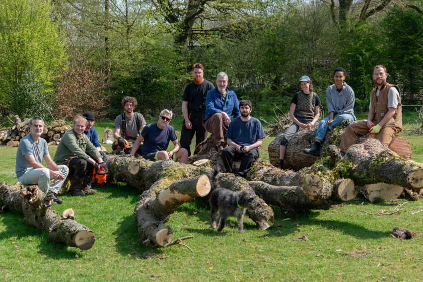 Photograph showing designers sat on and around felled tree