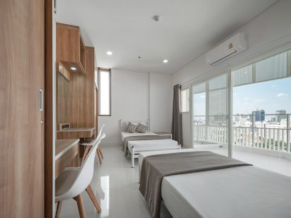 Bedroom in Bangkok apartment with two beds on opposite ends of room and views of city