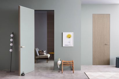 One open door and one closed door by Lualdi in a teal hallway