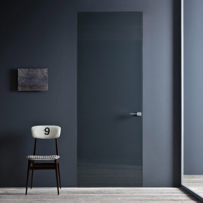 Photograph of grey door with chair beside it