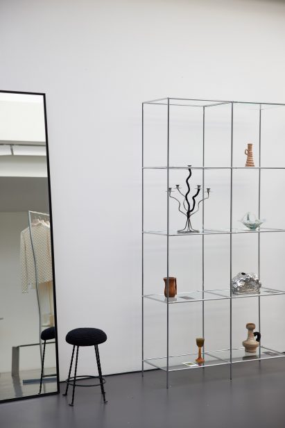 Image of a stool with a woven seat beside shelving at the Róhe Frames pop-up