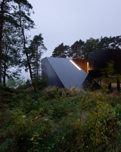 Sloping house clad in grey weathered timber by Saunders Architecture