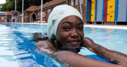 A girl wearing a large green swimming cap in a pool