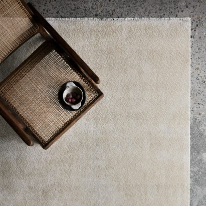 Photograph showing cool-toned living room with neutral-coloured rug