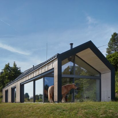 Photograph showing single-level gabled house looking over countryside with horse