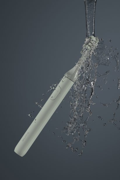 A green toothbrush being splashed with water