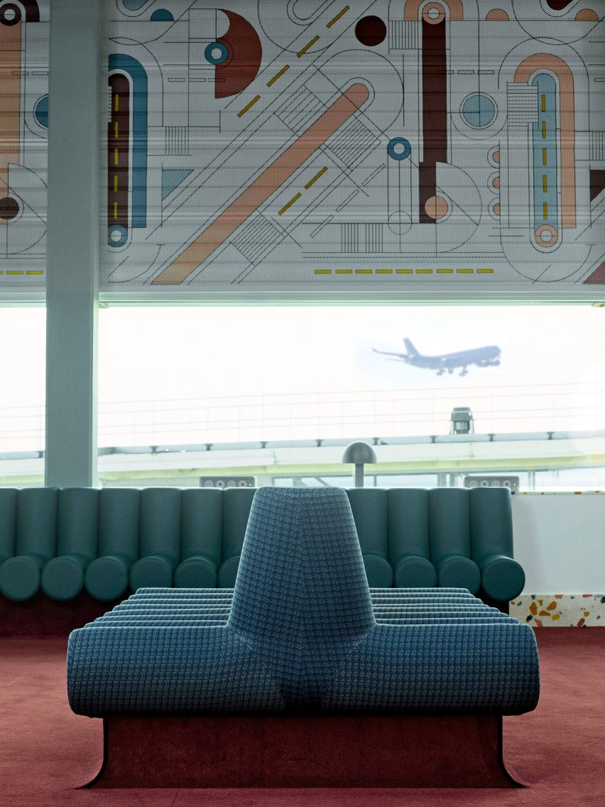 Photograph showing airport departure lounge with abstract mural above windows and green seating