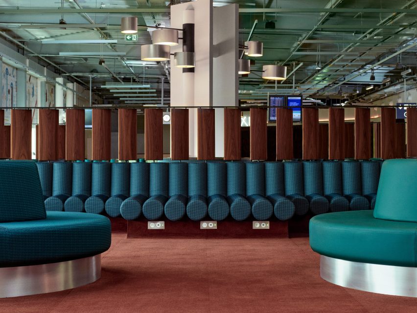 Photograph showing airport departure lounge with abstract mural above windows and green seating