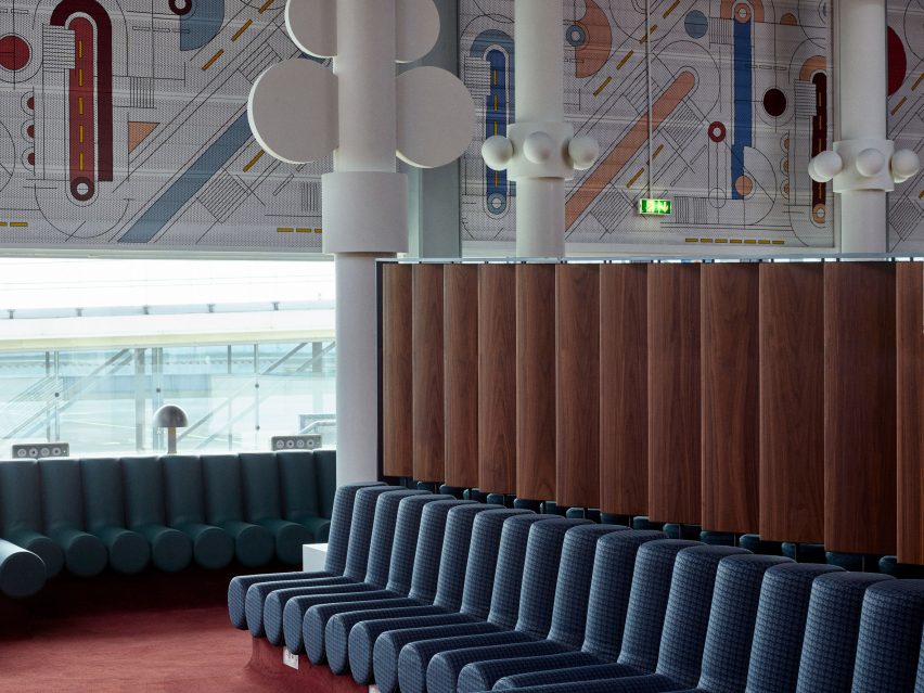 Photograph showing airport departure lounge with green bench seats and large tree-like rounded white sculptures