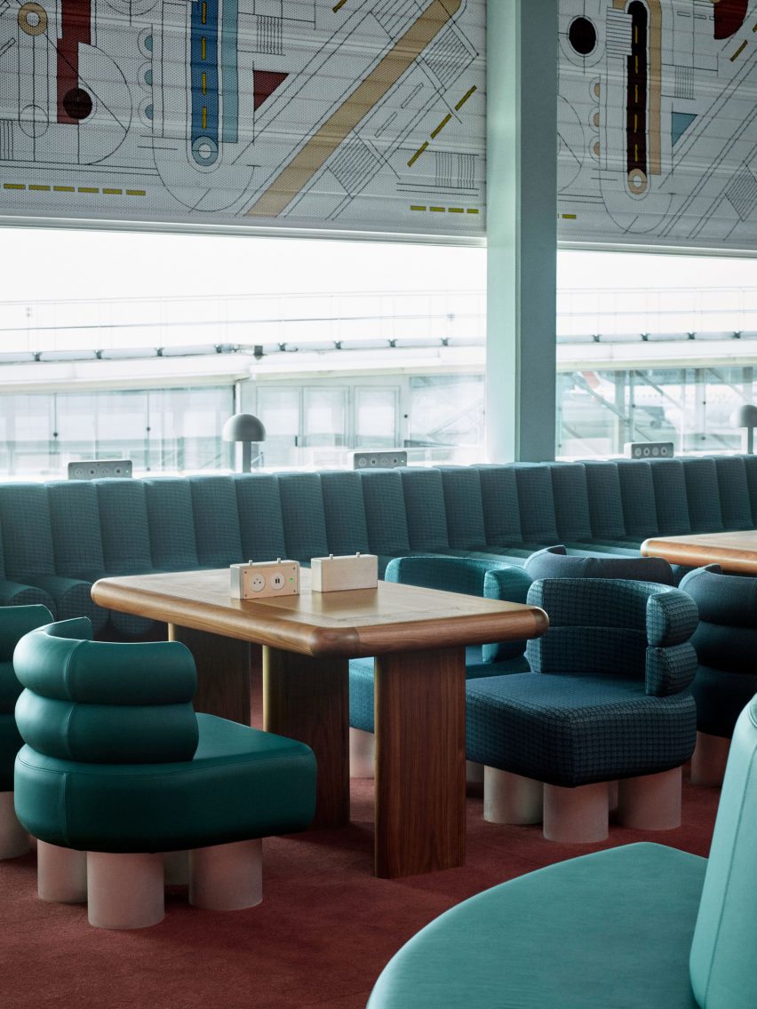 Photograph showing airport departure lounge with abstract mural above windows and green seating