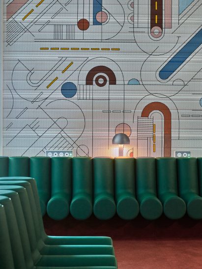 Photograph showing airport departure lounge with green bench seats and abstract mural behind