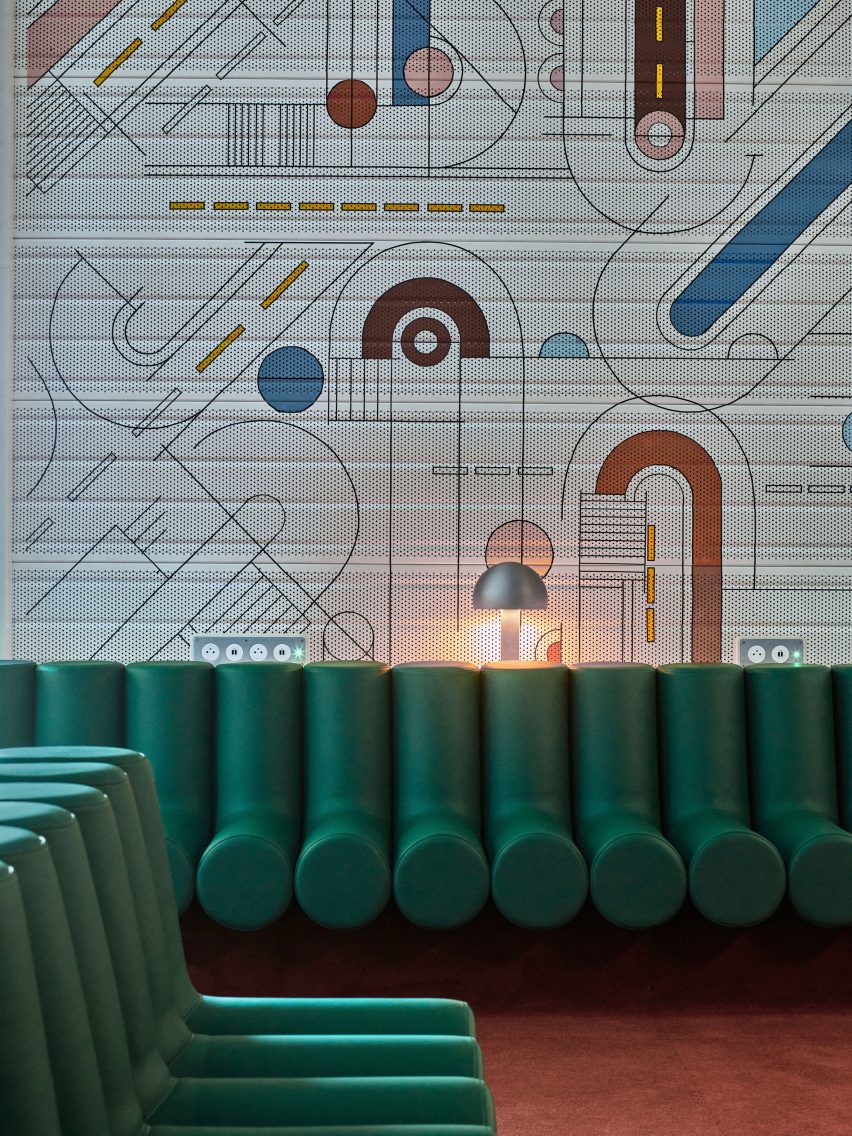 Photograph showing airport departure lounge with green bench seats and abstract mural behind