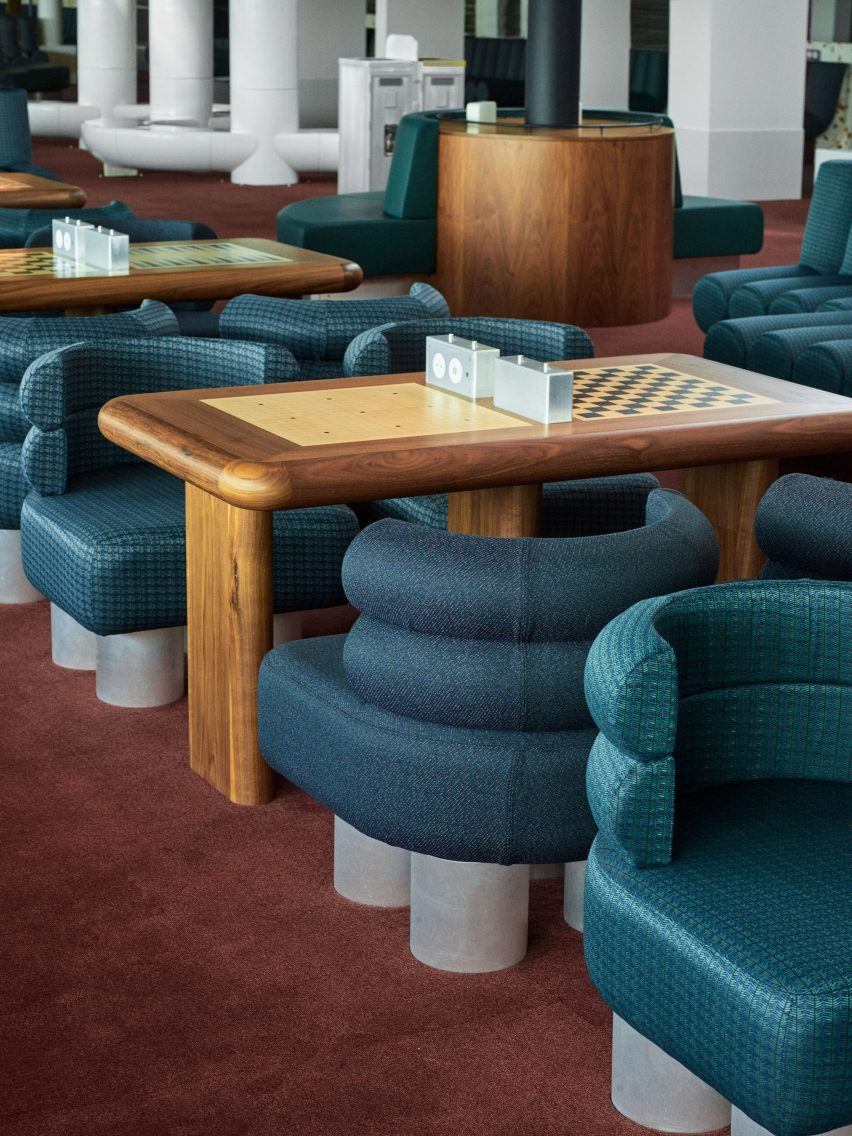 Photograph showing airport departure lounge with green seating and wooden chess tables