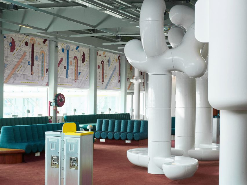 Photograph showing airport departure lounge with green bench seats and large tree-like rounded white sculptures
