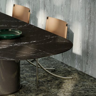 Photograph showing dining chairs and table with marble patterned wall, floor and tabletop