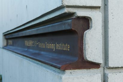Scrap rail metal sign reading Totetsu Training Institute embedded in concrete wall