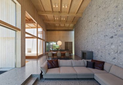 Sunken living room in open-plan living area by Archipatch with exposed beams and grey wall