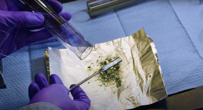 Close-up of person in a lab holding a vial and spatchula