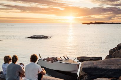 Small white electric boat tied to a mooring at sunset