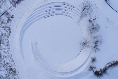 Aerial view of amphitheatre by Z'scape with curved benches covered with snow