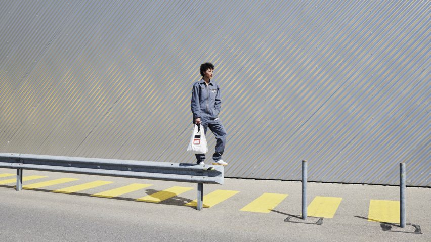 Person in overall carrying a white bag