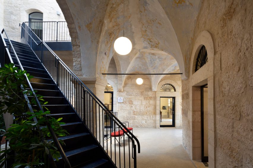 Black metal staircase cutting through a stone central courtard