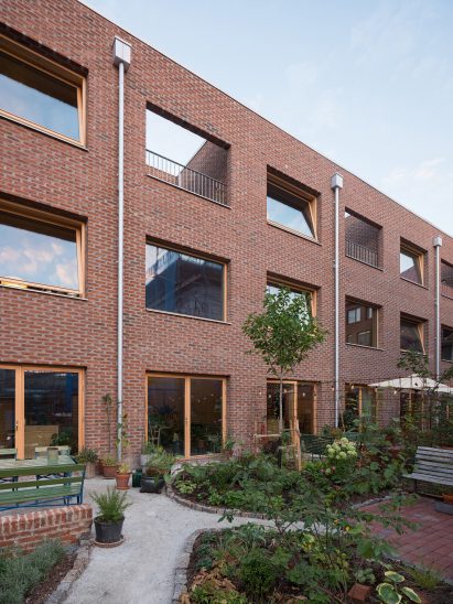 Image of the rear of Twelve Houses and the paved gardens with green plant beds