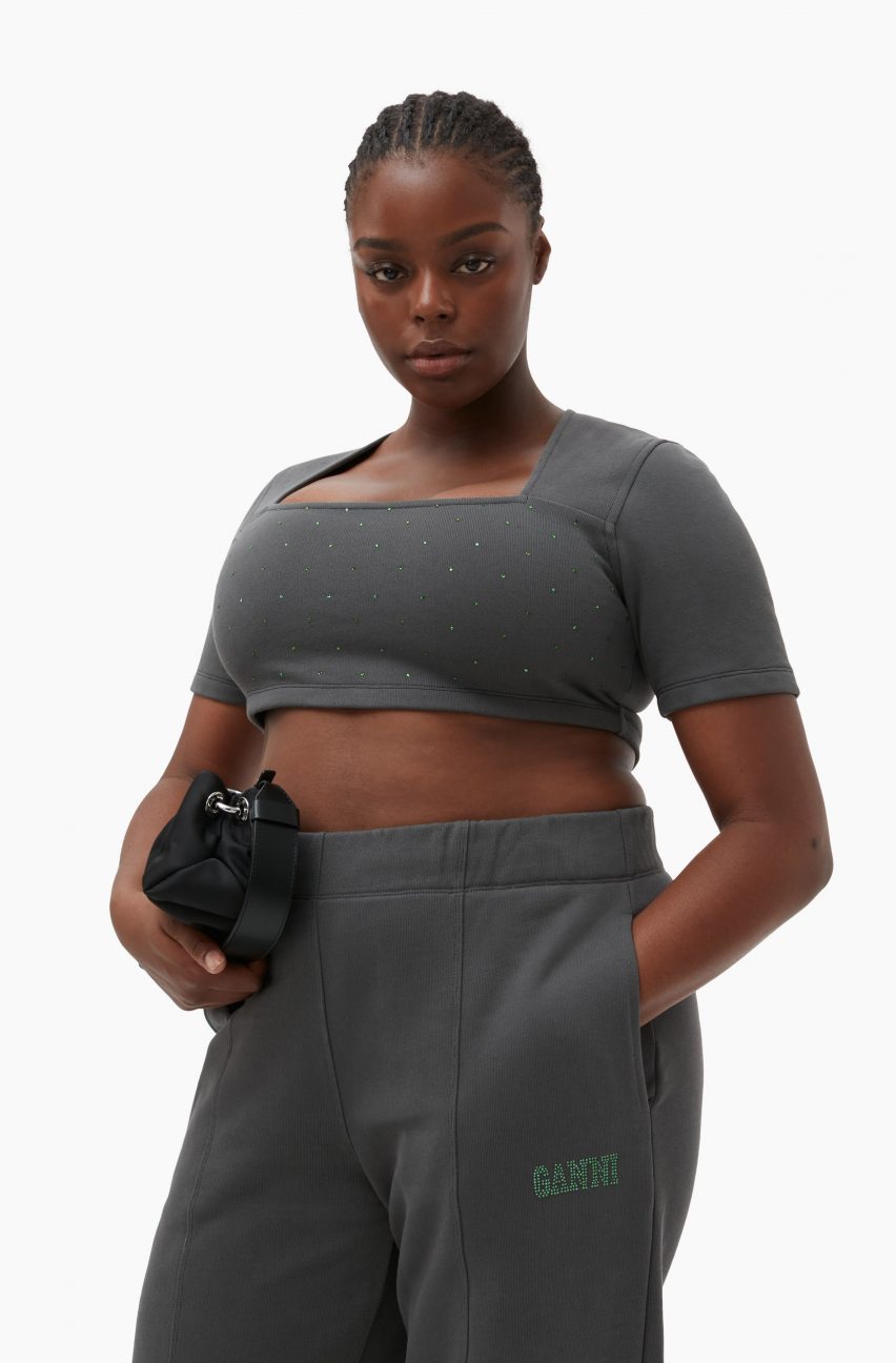 A woman wearing a grey crop top and tracksuit bottoms