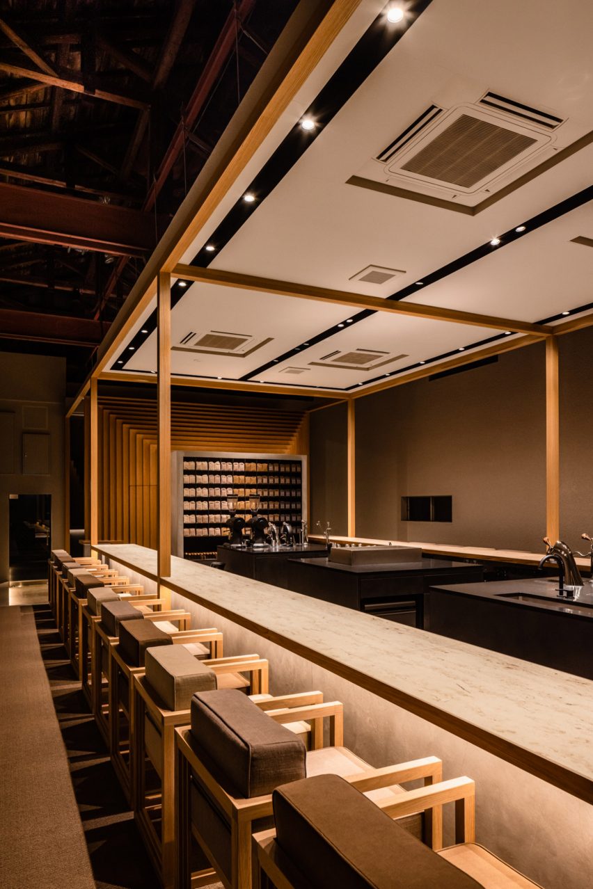 long coffee counter with wooden stools lit from above