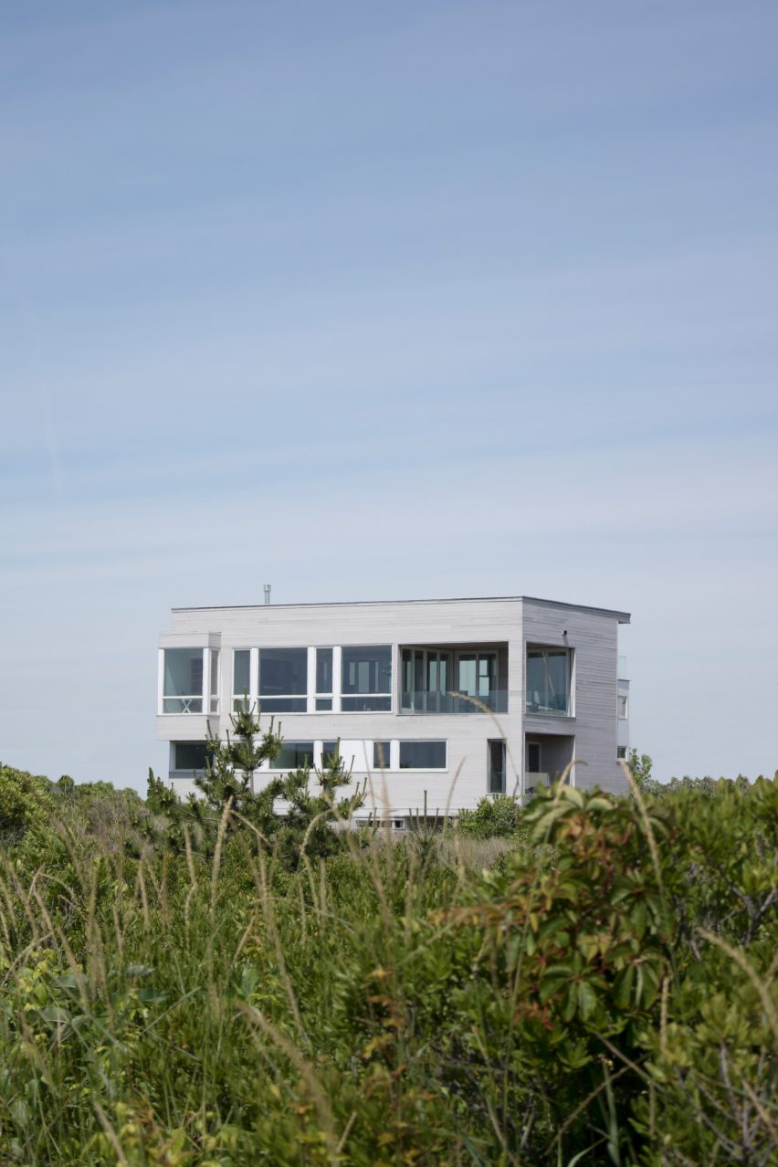 A grey cube shaped house on grass