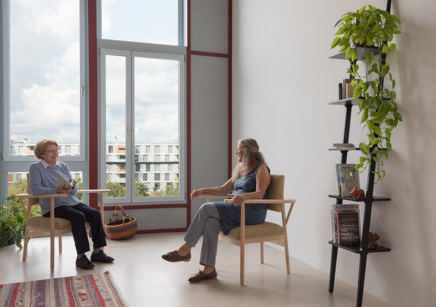 Two people sat on Lotte armchairs by Sarah Hossli