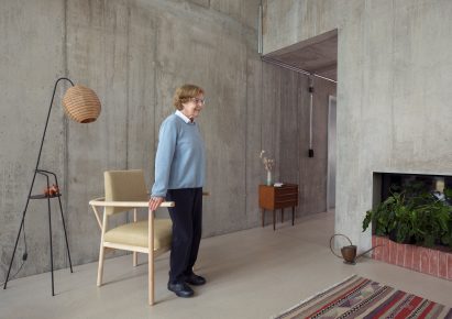 Elderly woman standing up from wooden chair