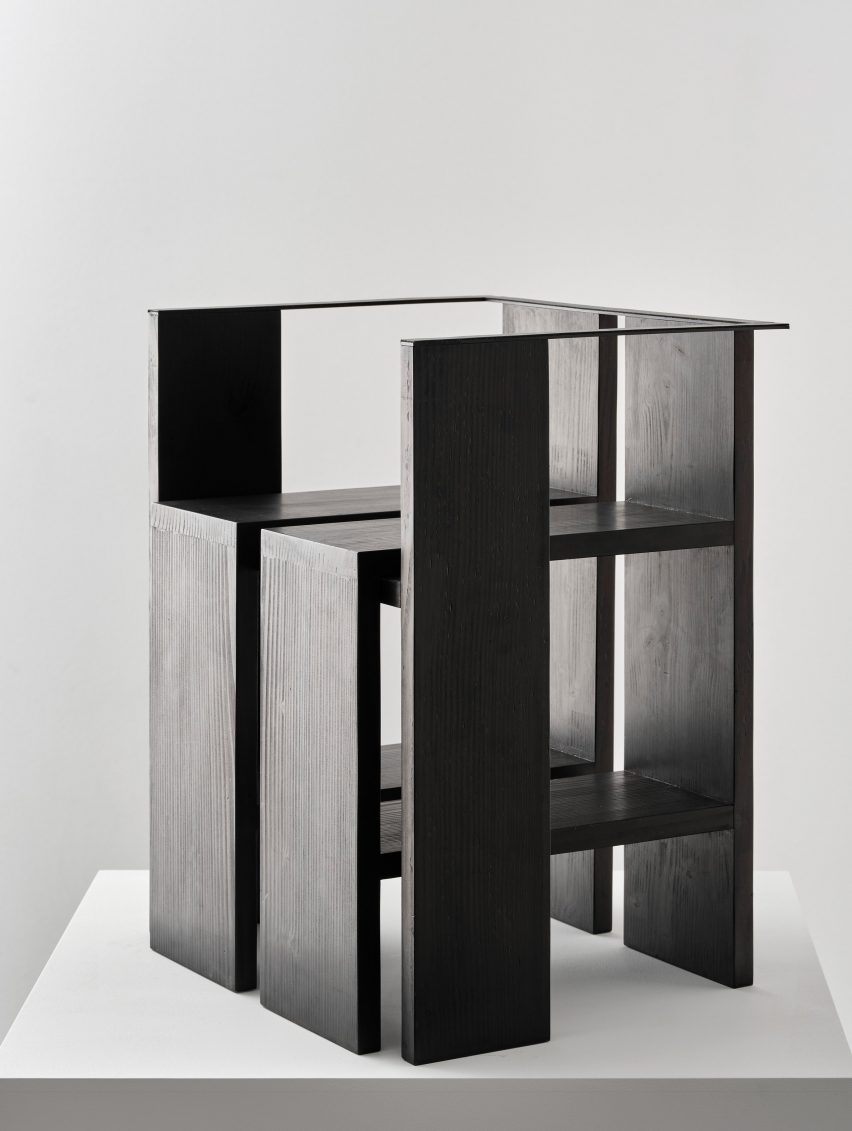 Photograph of black chair on white plinth in front of white background