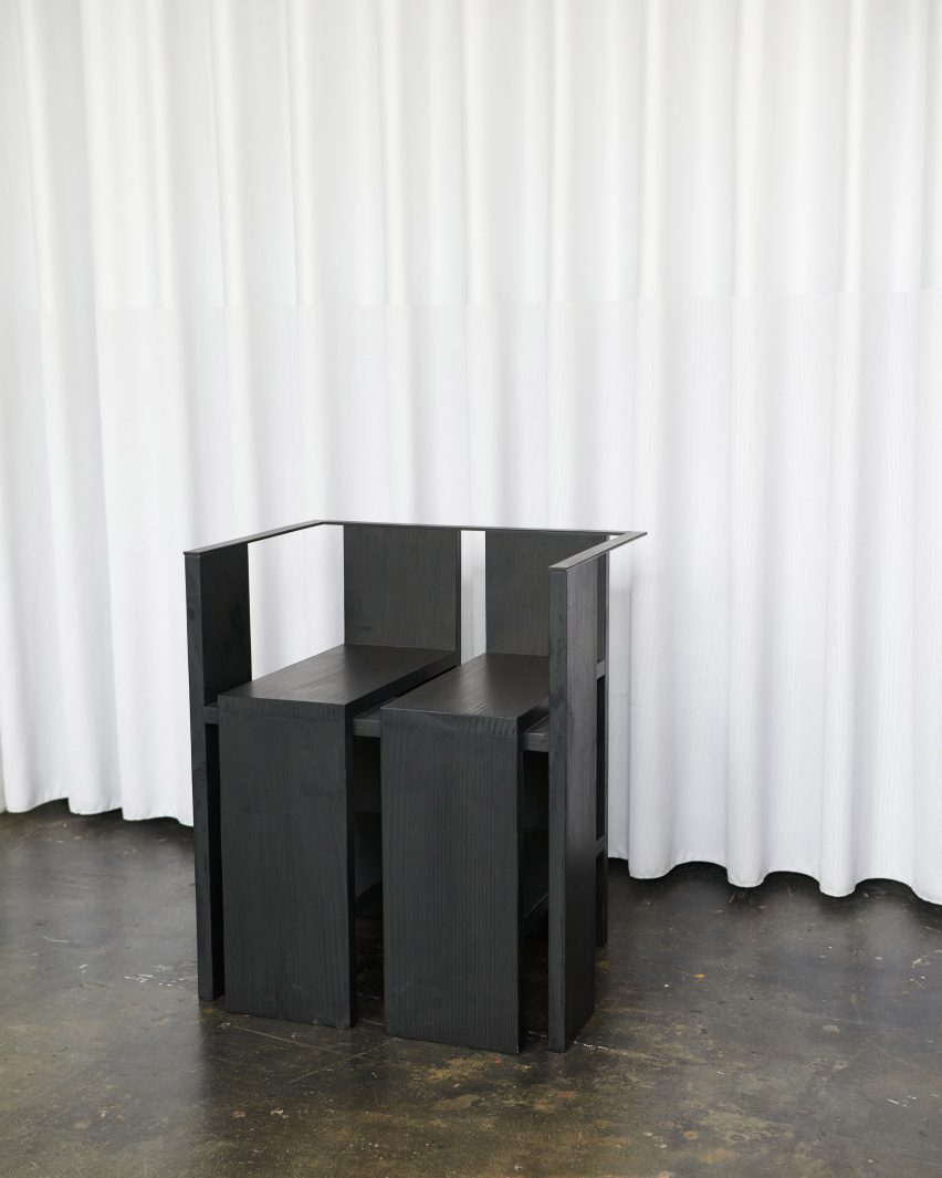 Photograph of black chair in front of white curtain