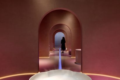 A photograph of a person walking through the exhibition’s earthy walls