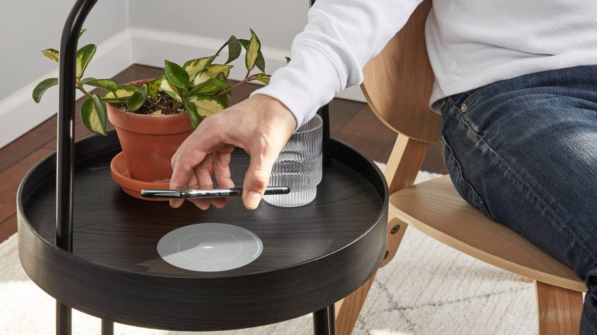 A man charging his phone on a wireless charger by Humanscale