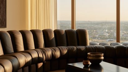 Black leather sofa next to windows with London view