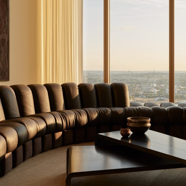 Black leather sofa next to windows with London view